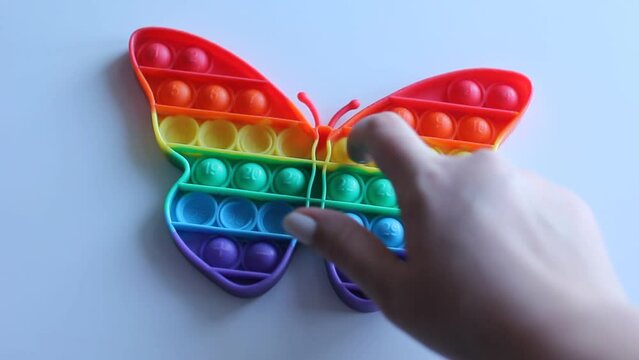 female hands holding a rainbow Toy antistress Pop it, poppit -new fidget toy, press rubber bubbles