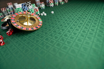 Casino. Gambling games theme.  Roulette wheel, dice and poker chips on the casino felt green table.