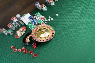 Casino. Gambling games theme.  Roulette wheel, dice and poker chips on the casino felt green table.