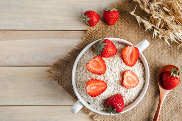 Oat muesli and fresh strawberries on wooden background. Healthy rustic breakfast.