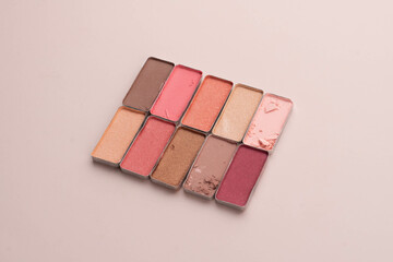 A broken eye shadow make up palette on a beige background. Beauty and cosmetic concept.