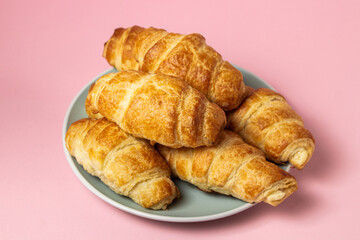 Fresh croissants on a pink background. Tasty breakfast. Traditional pastries.