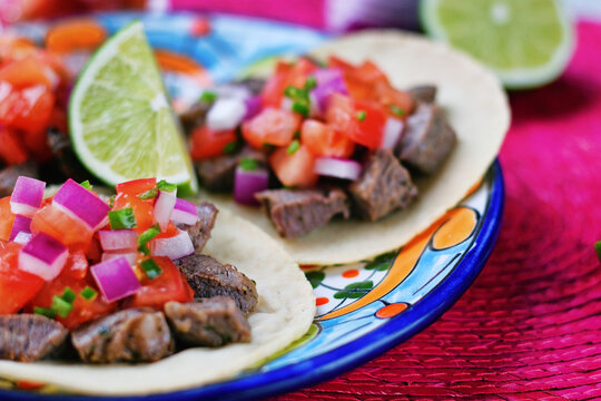 ピンク背景のメキシコ料理の美味しい牛肉のタコス 　ピコ・デ・ガジョとライムを添えて　Delicious Mexican beef tacos with pico de gallo and lime on pink background