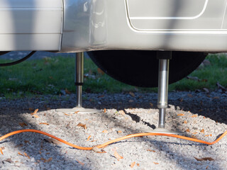 Close view of two hydraulic levelling jacks used to level a motorhome recreational vehicle on a gravel surface.Technology