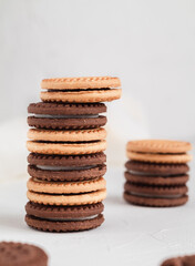 Stack of milk and chocolate cookies with cream filling on a white table.