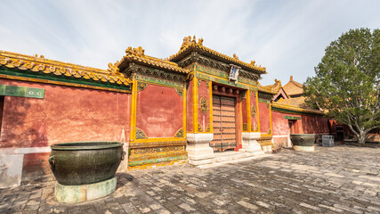 Eine große rote Mauer sowie ein Holztor mit vielen chinesischen dekorativen Elementen grenzen in...