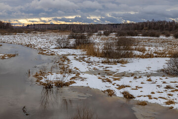 Spring flood. Evening landscape with a river and melting snow.