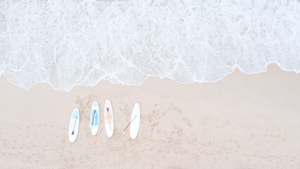 four surfboard are placed on the sandy Beach and sea wave aerial top view from drone