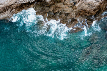 Aerial top view of sea waves hitting rocks, photograph drone of point view