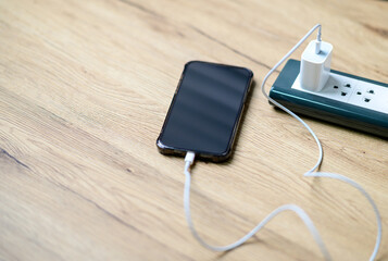 smart phone charger plugged on wooden with plugged at home.