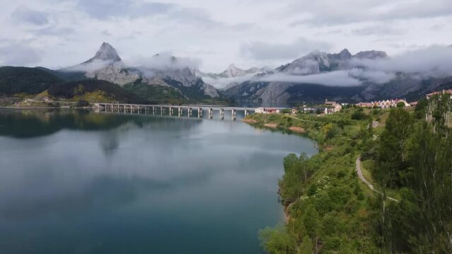 Ria&ntilde;o, Castile and Leon, Spain - Aerial Drone View of the Famous Bridge, Cloudy Mountains and Water (Mirror) Reservoir at Nature Park Monta&ntilde;a de Ria&ntilde;o and Mampodre