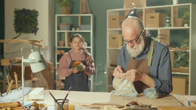 A Caring Grandfather Teaches his Teenage Granddaughter to Knit in a Home Workshop. Handicraft, Hobby. Communication of Generations, Happy Family Time Together, Transfer of Skills. Mental Health.