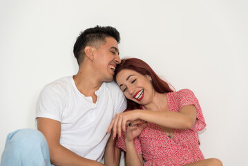 laughing couple, dark-haired boy in white T-shirt, red-haired girl in red dress, with neutral background