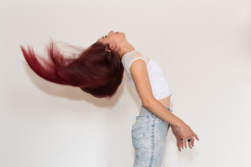 red-haired girl shaking her hair, smiling, with neutral background