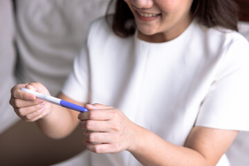 Young Asian woman are happy when they see the results of a pregnancy test.