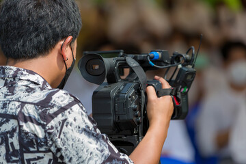 Video camera operator working with his equipment. video cinema production. Covering an event with a...
