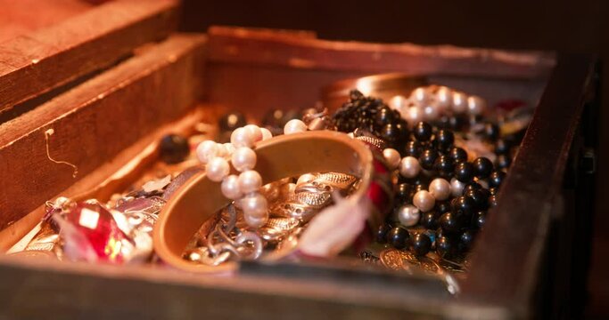 Naughty black dachshund smells plundered treasures lying in open wooden chest IN cabin of pirate ship during voyage extreme closeup
