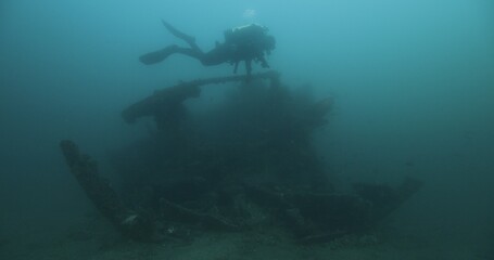  Scuba diver swims over old shipwreck.