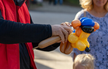 man making funny balloon dog figure for children