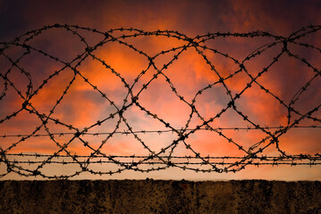 Prison. The wall of the prison with barbed wire against the backdrop of the setting sun. Law and law
