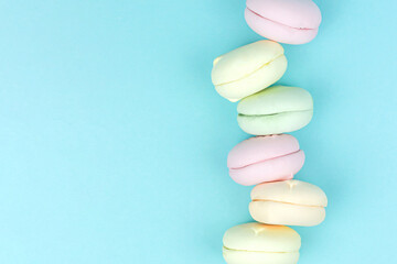 Sweet and colourful marshmallow looks like french macaroons. Beautiful variety of macaroons on pastel blue background.