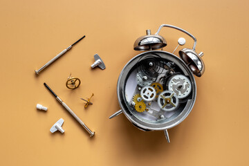 Watch mechanism and watchmaker tools near open alarm clock