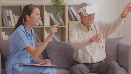 Asian Female doctor give advice elderly patient using VR or Virtual Reality glasses headset pointing objects or touching tracking health.Happy senior man having fun with goggle using VR enjoy at home