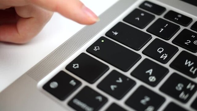 Hand pressing capslock key on modern laptop keyboard close-up slow motion video