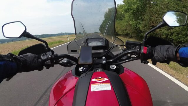 POV of Biker rides a motorcycle on a scenic Asphalt road in Austria. Steering wheel view. Motorcyclist on Motorbike goes on a Beautiful landscape highway. First-person view. Solo motorcycle travel.