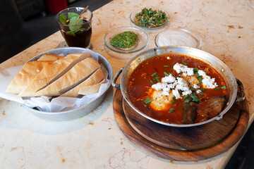 Shakshouka, popular in the Middle East and Israel, is a Maghrebi dish of eggs poached in a sauce of tomatoes, olive oil, peppers, onion and garlic, and served with fresh bread, tea and herbs.
