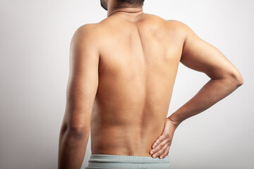 shirtless male torso from behind showing pain in lower back spine