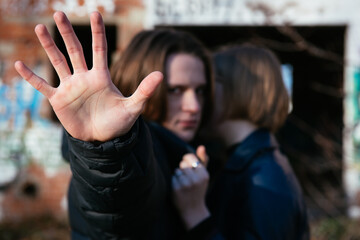 stop the war. Russian guy with long hair protects Ukrainian blonde girl. object out of focus