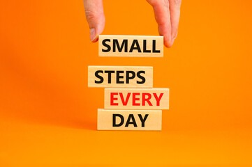 Small steps every day symbol. Concept words Small steps every day on wooden blocks. Businessman hand. Beautiful orange table orange background. Small steps every day business concept. Copy space.