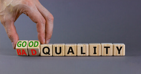 Good or bad quality symbol. Businessman turns cubes and changes words bad quality to good quality. Beautiful grey table grey background. Business good or bad quality concept, copy space.