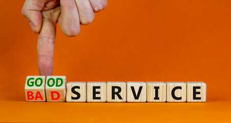 Good or bad service symbol. Businessman turns cubes and changes words bad service to good service. Beautiful orange table orange background. Business good or bad service concept, copy space.