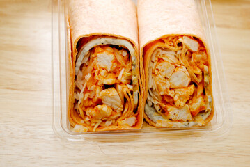 A Cut in Half Hot and Spicy Buffalo Chicken Wrap in a Plastic Package