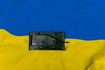 Stop the war between Russia and Ukraine. Attack concept background with a Russian tank on the Ukrainian flag.