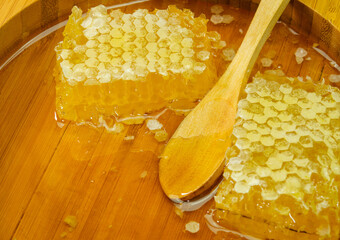 Honey with honeycomb and wooden spoon in a wooden plate