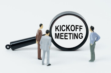 On a white background, figures of businessmen and a magnifying glass with the inscription - Kickoff Meeting