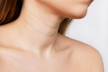 Сropped shot of a young woman with lines on the neck isolated on a white background. Wrinkles,...