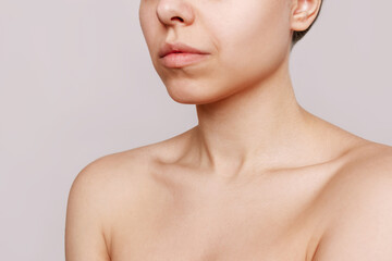 Cropped shot of a young caucasian woman with a protruding collarbone isolated on a beige...