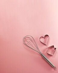 Steel whisk house and heart-shaped cutter flat lay top view. Confectionery cooking concept with...