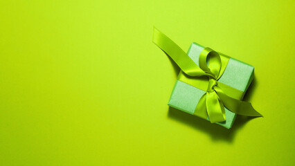 Banner of brown paper gift box with a yellow ribbon bow on bright green background on the right with copy space. Flat lay Saint Patrick's day father mother day and presents concept