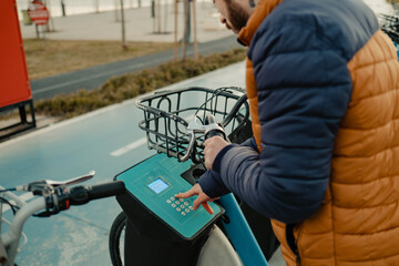 Bike rental machine, young man rents a bike, a rental vending machine that says start on the screen, a beach excursion and green transportation, selective focus on vending machine, noise effect