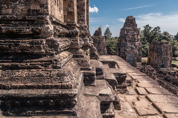 Fototapeta premium Ruins of ancient Cambodian temple in Angkor complex with trees in background, Siem Reap, Cambodia