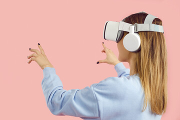 Happy smart teen girl wearing VR gear headset experiences augmented reality, feels virtual objects...