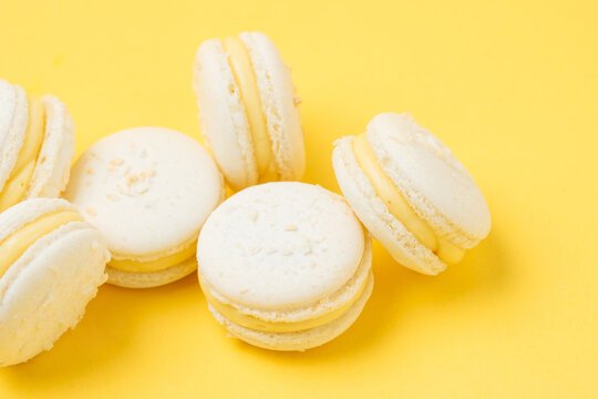 Pile of vanilla macarons on yellow background