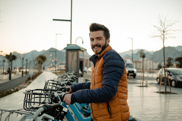 Rental bike, the young man rents a bicycle for a ride, smiling happy man holding the steering wheel of the bicycle, a stroll on the beach. Selective focus, noise effect.