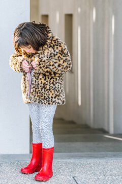 Girl putting ion fur coat near stairway