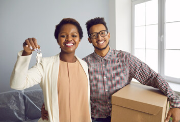 Portrait of overjoyed young multiethnic family buyers hold keys to new home moving in together....